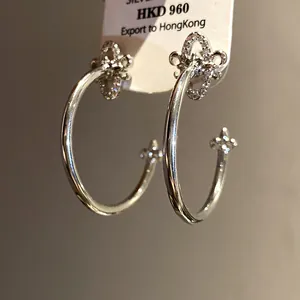 Detailed macro view of elegant silver fleur-de-lis C-shaped earrings with pavé zircons