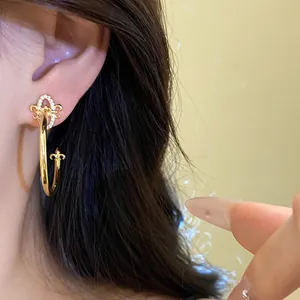 Close-up of elegant gold fleur-de-lis C-shaped hoop earrings with sparkling zirconia.