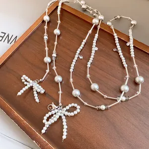 Detailansicht einer Perlenkette mit eleganten Perlen-Schleifenanhängern auf Holzbrett.