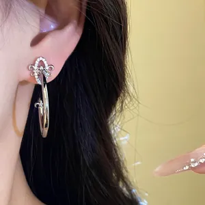 Detail showing silver needle iris flower C-shaped stud earring with zircon inlay.