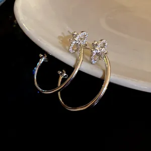 Close-up of silver fleur-de-lis C-shaped earrings with sparkling cubic zirconia.
