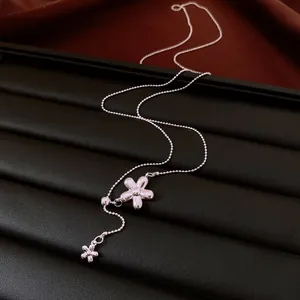 Detail shot of a silver flower tassel necklace on a black leather jewelry display.