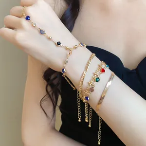 Macro view of layered gold bracelets with colorful crystal accents and varied chain links