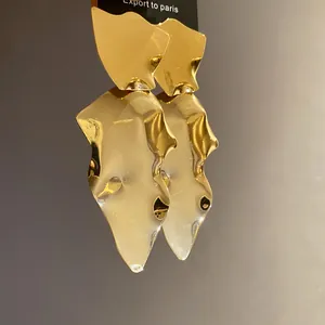 Detail view of bold gold irregular hammered metal drop earrings with polished mirror finish.