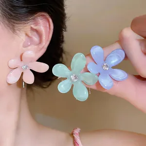 Detalle de pendientes de flores en resina de colores con circonitas y pernos de plata.