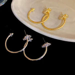 Detail view of C-shaped hoop earrings featuring iris flower motifs and cubic zirconia.