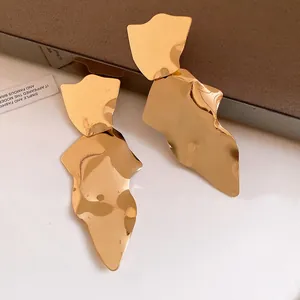 Close-up of gold-tone irregular metallic earrings with a retro exaggerated style