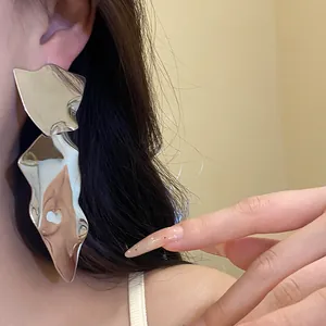 Close-up of silver irregular metallic earrings with shiny finish worn on model's ear