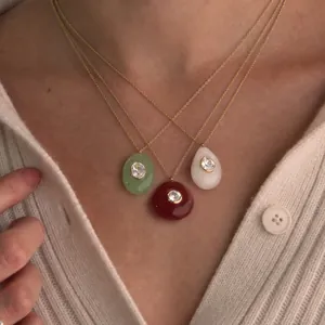 Gros plan de trois colliers goutte en résine colorée portés par un mannequin
