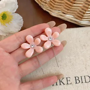 Primer plano de pendientes de flor de resina rosa con circón y cadenas de plata