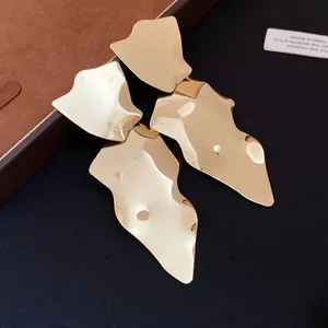 Detail view of bold irregular gold geometric drop earrings with shiny metallic finish