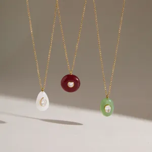 Vue rapprochée de trois élégants pendentifs en résine sur chaînes en titane doré avec zircons.