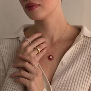 Élégant collier avec pendentif en résine rouge et chaîne dorée sur un mannequin.