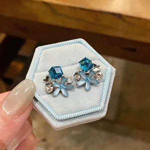 Close-up detail of elegant blue floral stud earrings with crystals in a velvet box