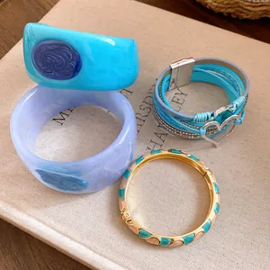 Set of stylish resin bangles and multi-layer heart charm bracelet on a book