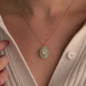 Gros plan d'un collier plaqué or avec un pendentif ovale vert porté sur un mannequin