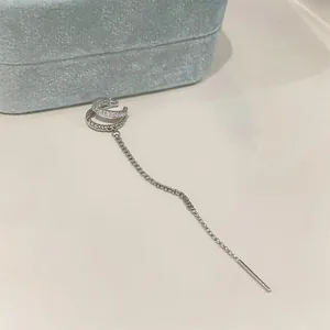 Close-up of elegant double-layered silver ear cuff with sparkling zircon and long tassel chain