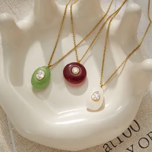 Gros plan de pendentifs en résine sur chaînes en acier titane doré en trois couleurs