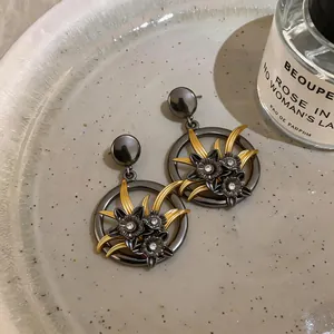 Primo piano di orecchini vintage grigio scuro con fiori dorati e strass incastonati