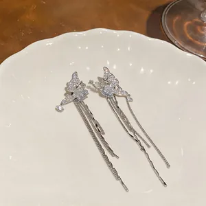 Detailed macro shot of silver butterfly tassel ear clips with sparkling zircon stones