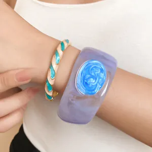 Close-up detail of a thick purple resin cuff and a slim teal enamel twisted bangle set
