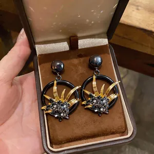 Dettaglio ravvicinato di orecchini vintage a fiori scuri con strass scintillanti.