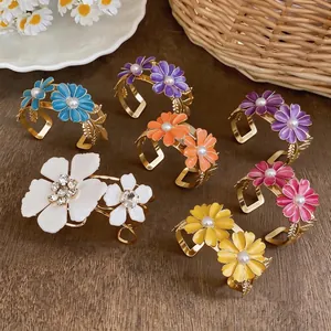 Colorful enamel daisy bangles with pearls on a rustic wooden background.