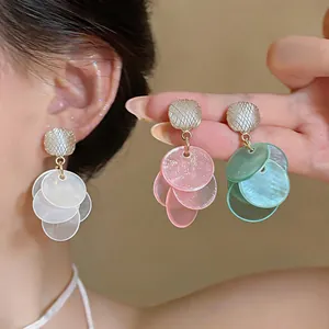 Close-up of cat-eye stone tassel earrings in white, pink and green shades on model