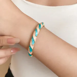 Detailed view of an elegant resin open bangle with turquoise and cream spiral drip oil patterns.