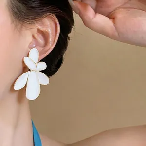 Oversized white enamel flower earrings with gold trim, stylish floral ear studs for women.