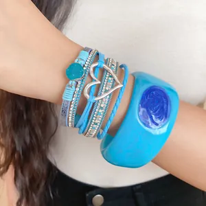 Detailed view of vibrant blue resin cuff bracelet with heart charm layered jewelry set