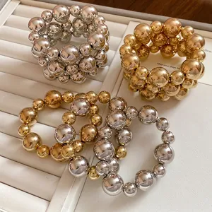 Set of smooth irregular metallic bead bracelets in silver and gold on a luxury jewelry tray.