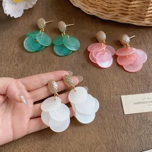 Macro view of multi-layered translucent disc tassel earrings in three soft colors