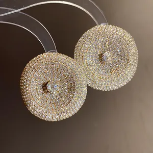 Primer plano de elegantes pendientes de botón redondos dorados con pedrería clara brillante