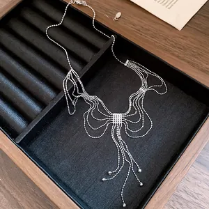 Vue détaillée d'un collier à franges en perles argentées en forme de ruban sur velours