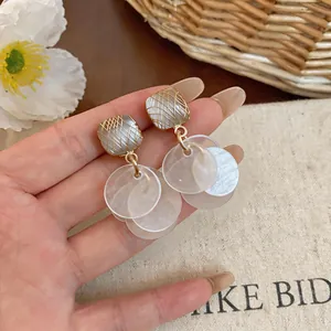 Close-up of cat's eye stone drop earrings with elegant translucent discs and golden mesh