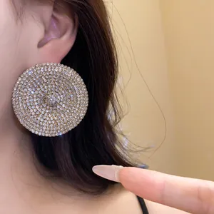 Primer plano de pendientes redondos con pavé de cristales brillantes en la oreja