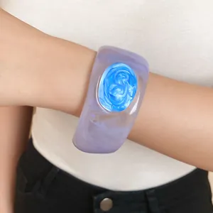 Close-up of a stylish purple resin bangle with blue swirl inlay on wrist