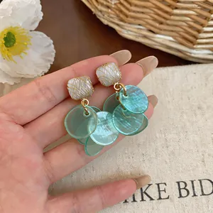 Macro view of Korean style teal tassel stud earrings with translucent round charms