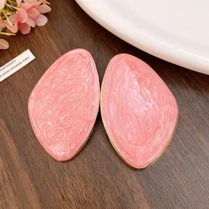 Macro di orecchini a goccia d'olio geometrici rosa con bordi dorati su legno scuro