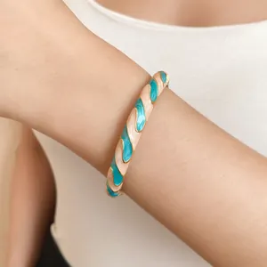Close-up of a chic resin enamel open bangle bracelet with teal and cream swirls