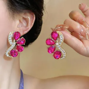 Detailed close-up of fuchsia teardrop crystal earrings with gold trim and small rhinestones