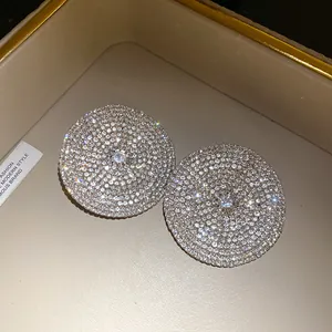 Detalle de los pendientes de botón redondos con cristales blancos brillantes