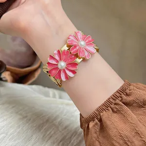 Detailed macro view of an elegant pink enamel daisy bangle bracelet with pearl centers.