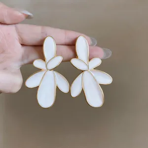 Detailed macro view of elegant white enamel flower earrings featuring polished gold edges