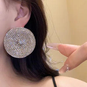 Detalle de pendientes redondos grandes totalmente incrustados con brillantes pedrerías