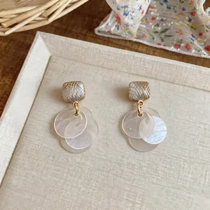 Close-up of cat's eye stud earrings with golden wire wrap and pearlescent disc charms