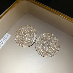 Vista macro de pendientes circulares con diamantes brillantes y aguja de plata.