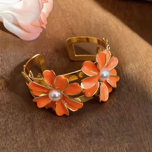 Close-up of elegant orange enamel daisy cuff bracelet with pearls on a rustic wood background