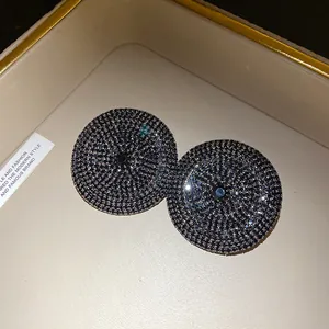 Detalle macro de elegantes pendientes redondos de pavé de diamantes de imitación negros.